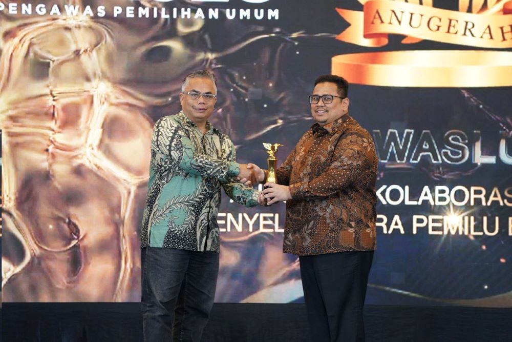 Ketua Bawaslu Rahmat Bagja menerima penghargaan Anugerah Kolaborasi Strategis Penyelenggara Pemilu bersama Media yang diserahkan oleh Wakil Pemred INDOPOSCO Folber Siallaga di Jakarta, Selasa (3/2/2026).
